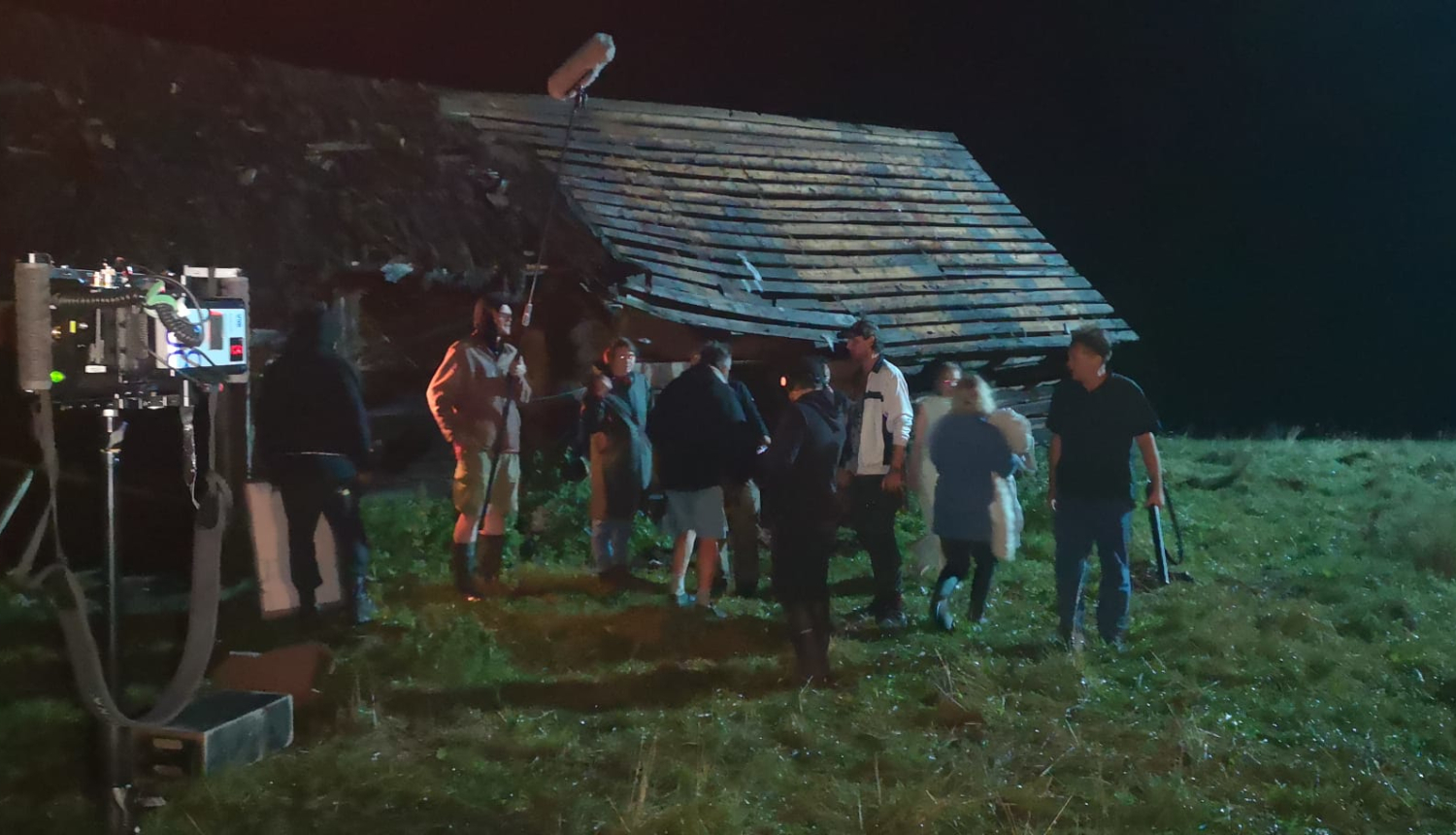 Filmas uzņemšana laukos - daudz cilvēku, fonā vecs šķūnis 