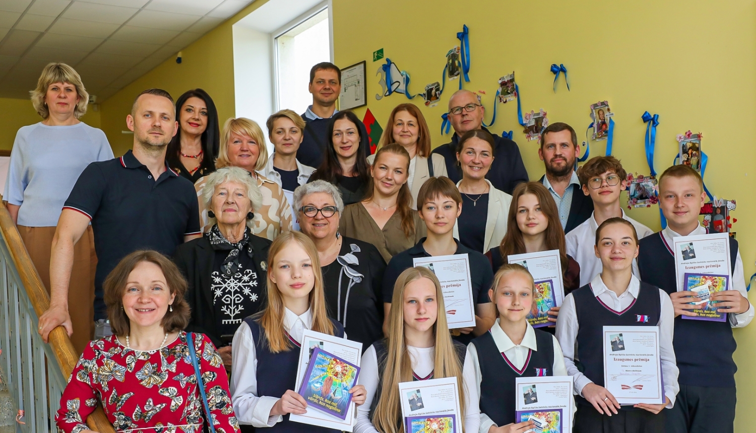 daudz cilvēku stāv uz kāpnēm ar diplomiem