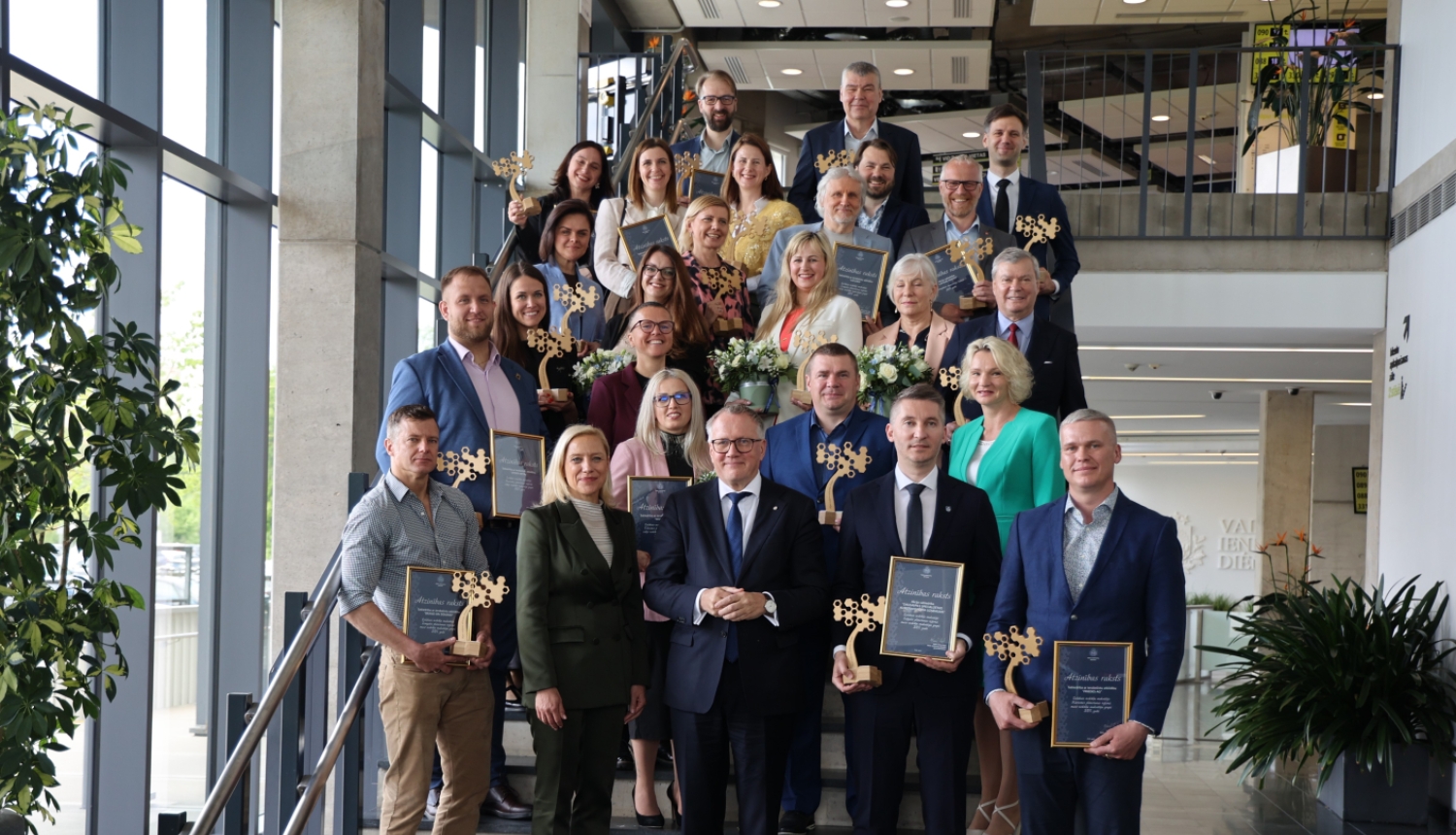 dadz cilvēki ar diplomiem stāv uz kāpnēm