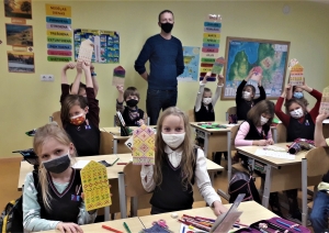 Bērni sēž solos un rāda savus darbus