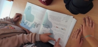 bērni ar pirkstiem rāda uz grāmatu