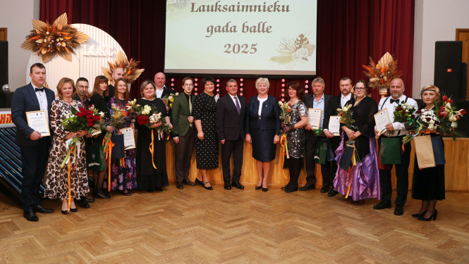 daudz cilvēki svinīgi stāv ar ziediem