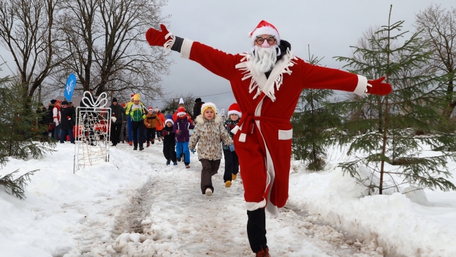 ziemassvētku vecītis skrien pa priekšu un iedzīvotāji aiz viņa