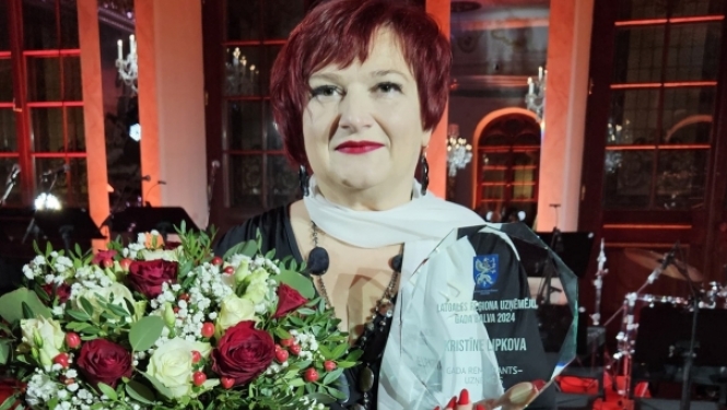 sieviete ar stikla balvu rokās un ziediem
