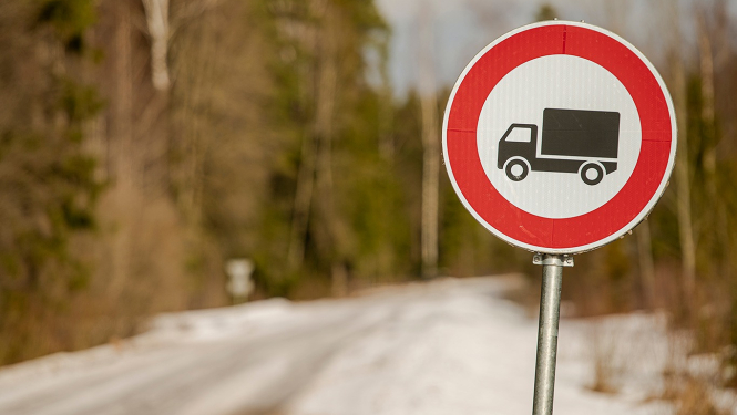 ceļa zīme ar smago auto unslikts ceļš fonā