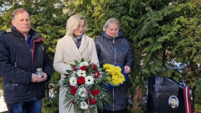 trīs cilveki pie kapavietas
