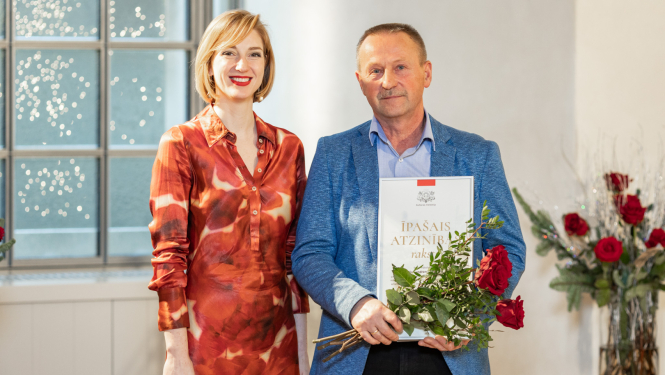 vīrietis un sieviete stāv ar apbalvojumiem rokā