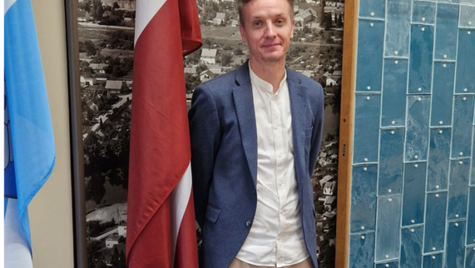 vīrietis stāv pie sienas ar karogiem