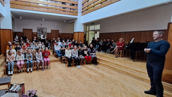 daudz bērnu zālē un vīrietis uzstājas 