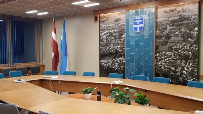 Sēžu zāle ar galdu, krēsliem un karogiem