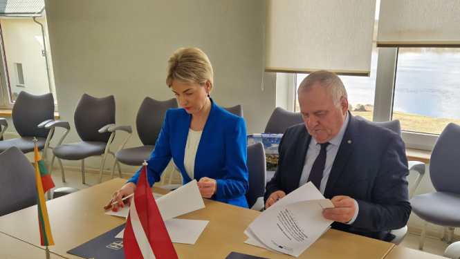 vīrietis un sieviete pie galda paraksta dokumentus