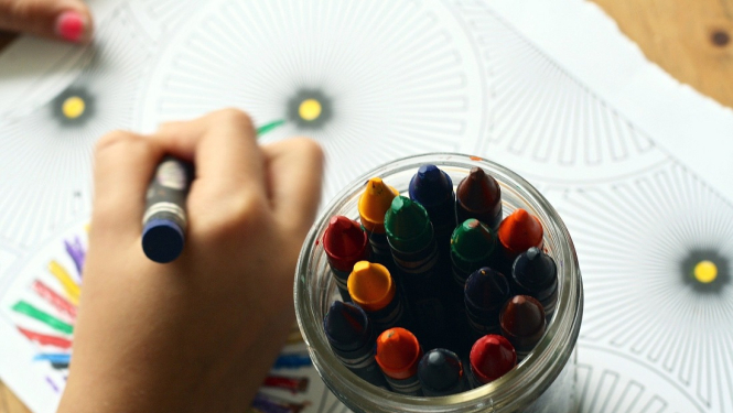 Bērna rokas, kas zīmē, un traukā krītiņi