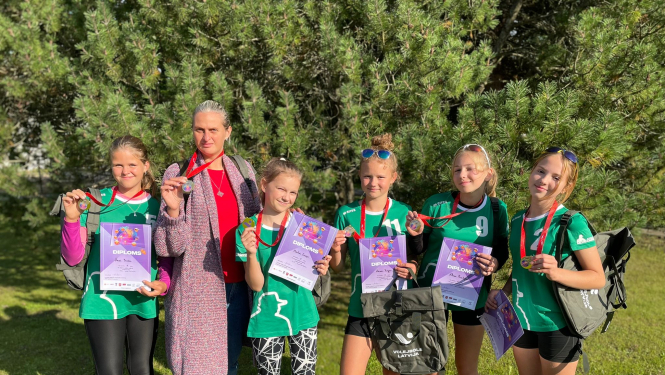 Jaunās volejbolistes un trenere ar medaļām un diplomiem