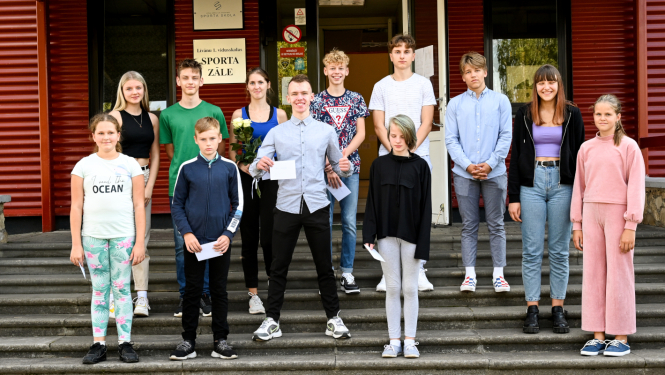 12 jaunieši stāv uz trepēm