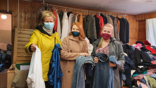 Trīs sievietes stāv pie drēbēm