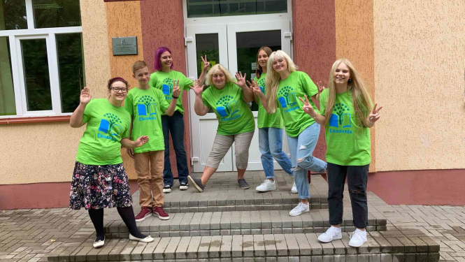 Cilvēki ar zaļiem t-krekliem pozē uz trepēm