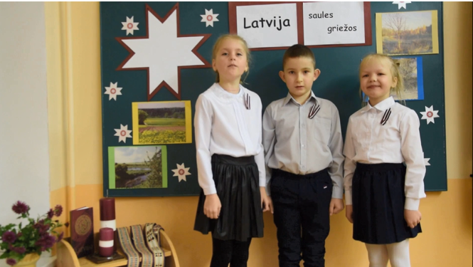 Trīs skolēni stāv klasē pie tāfeles