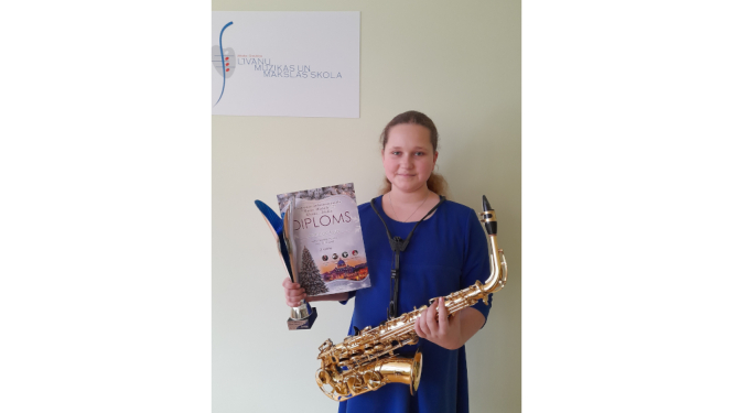 Meitene ar saksofonu, kausu un diplomu