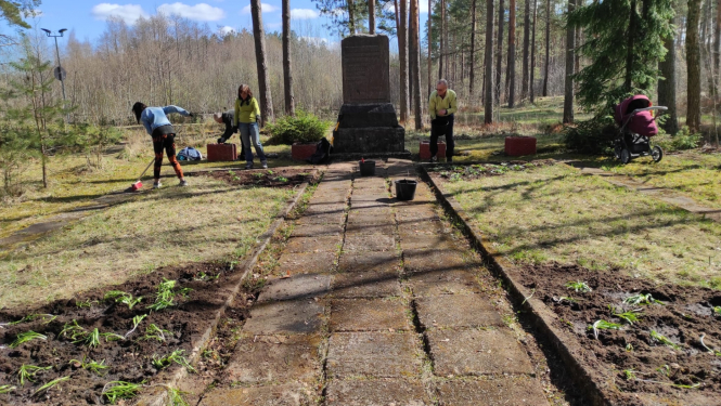 Cilvēki kopj apkārt piemineklim