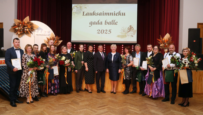 daudz cilvēki svinīgi stāv ar ziediem