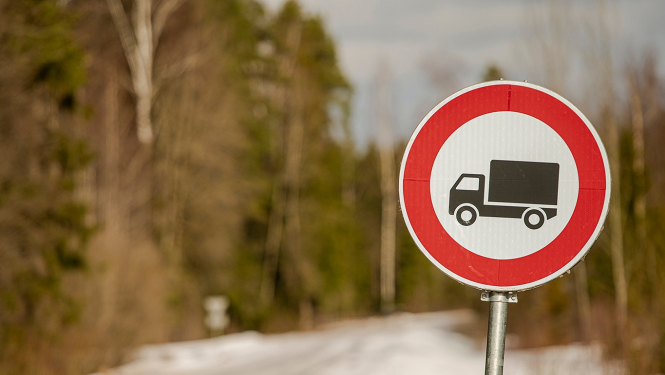 ceļa zīme ar smago auto unslikts ceļš fonā