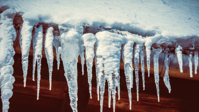 lāstekas, kas karājas pie apsniguša mājas jumta