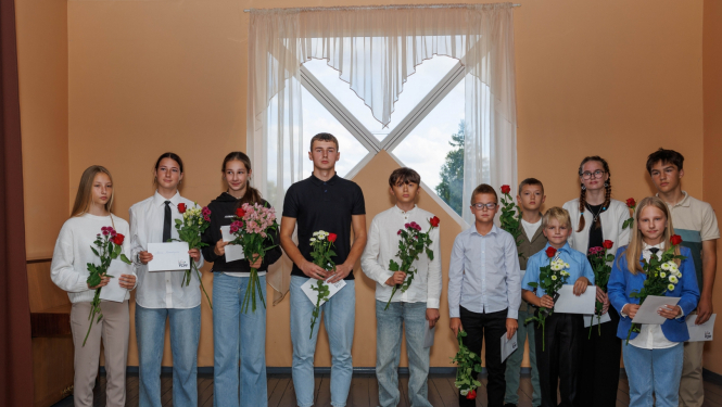 bērni stāv rindā ar ziediem un aploksnēm