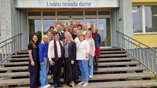 daudz cilvēku pozē uz kāpnēm