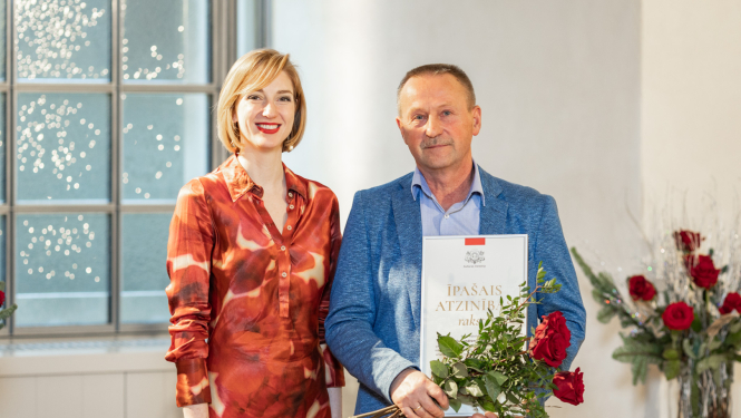 vīrietis un sieviete stāv ar apbalvojumiem rokā