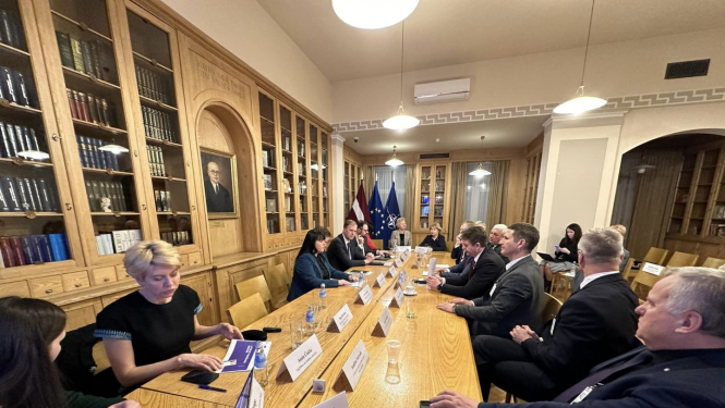 daudz cilvēku sēž ap galdu - sarunas