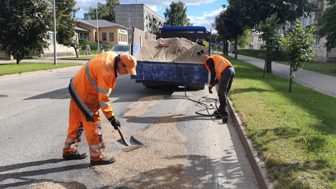 divi ceļa remontstrādnieki remontē ielu
