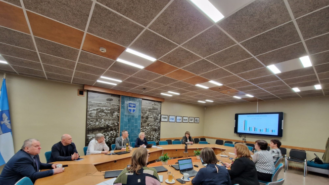 vairāki cilvēki sēž ap apaļo galdu apspriede