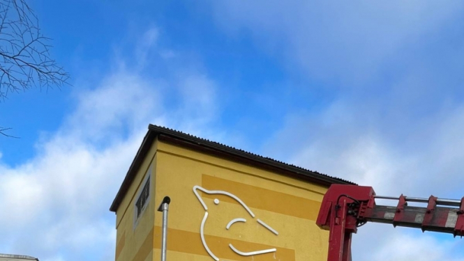 ar celtni uzstāda metāla skulptūru putniņu