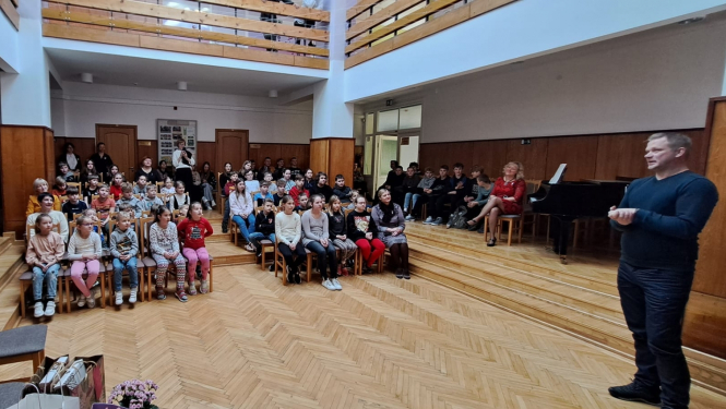 daudz bērnu zālē un vīrietis uzstājas 