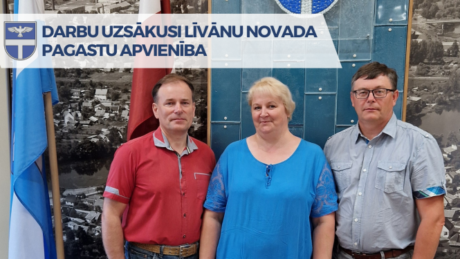 divi vīrieši un sieviete stāv pie karoga