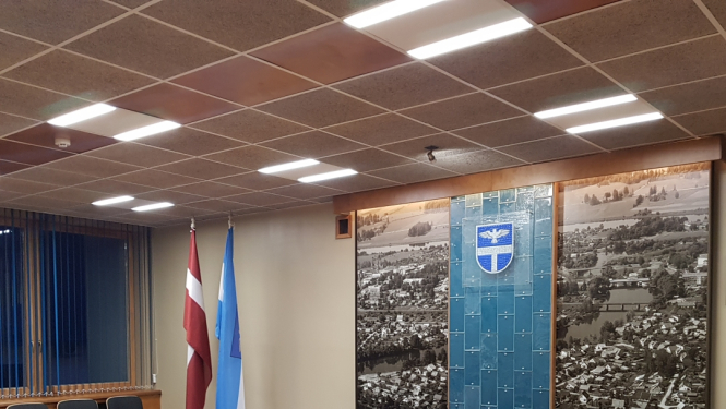 Sēžu zāle ar galdu, krēsliem un karogiem