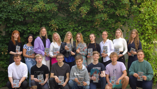 daudz jauniešu divās rindās pozē pie zaļas augu sienas