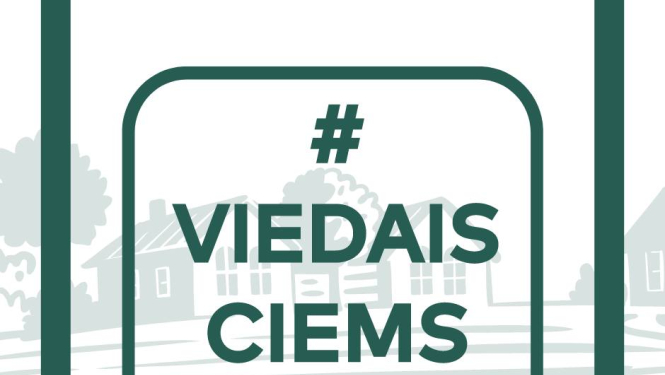 ciems fonā ar ēkām un pa virsu uzrakstīti burti - zaļš 