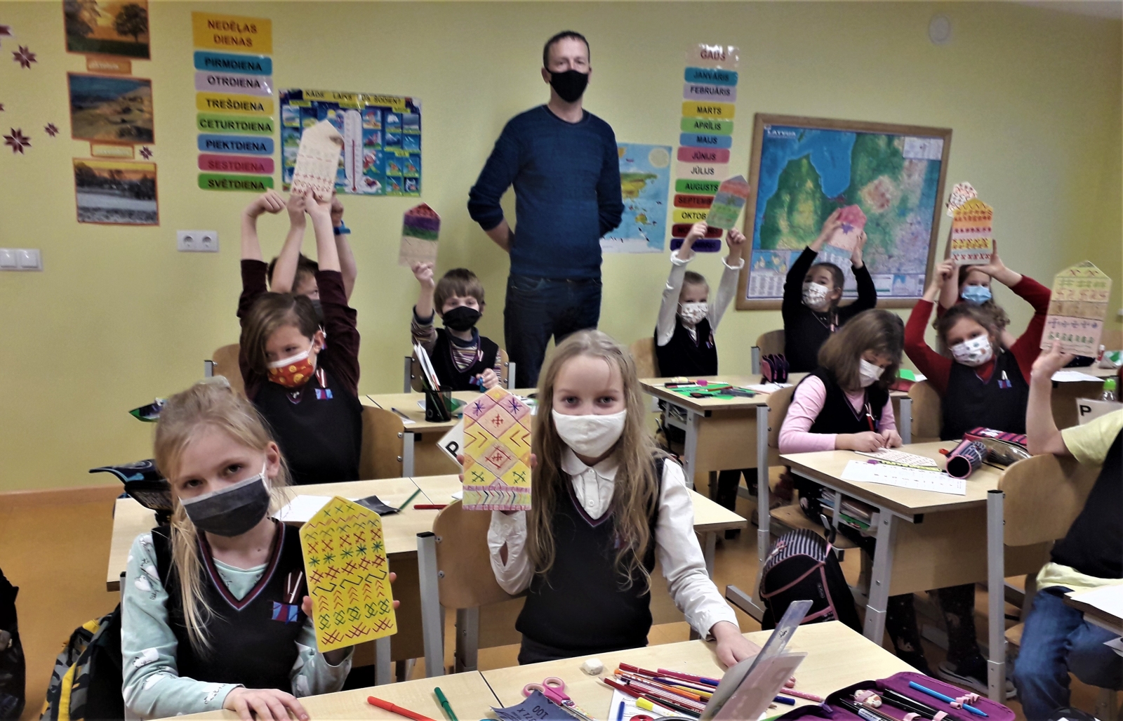 Bērni sēž solos un rāda savus darbus
