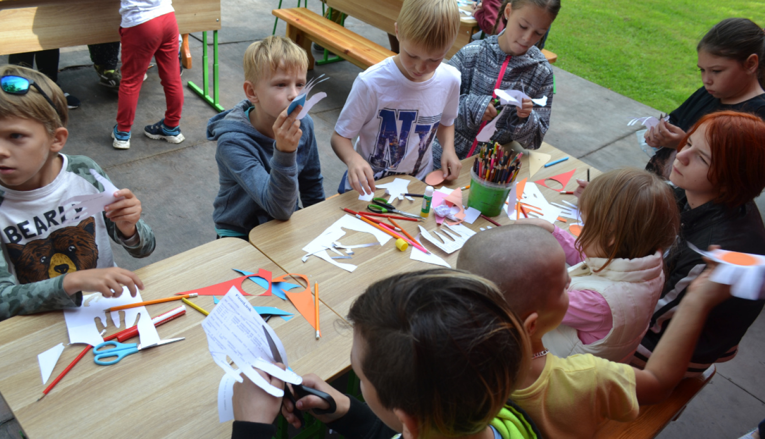 Bērni pie galda griež un krāso papīru