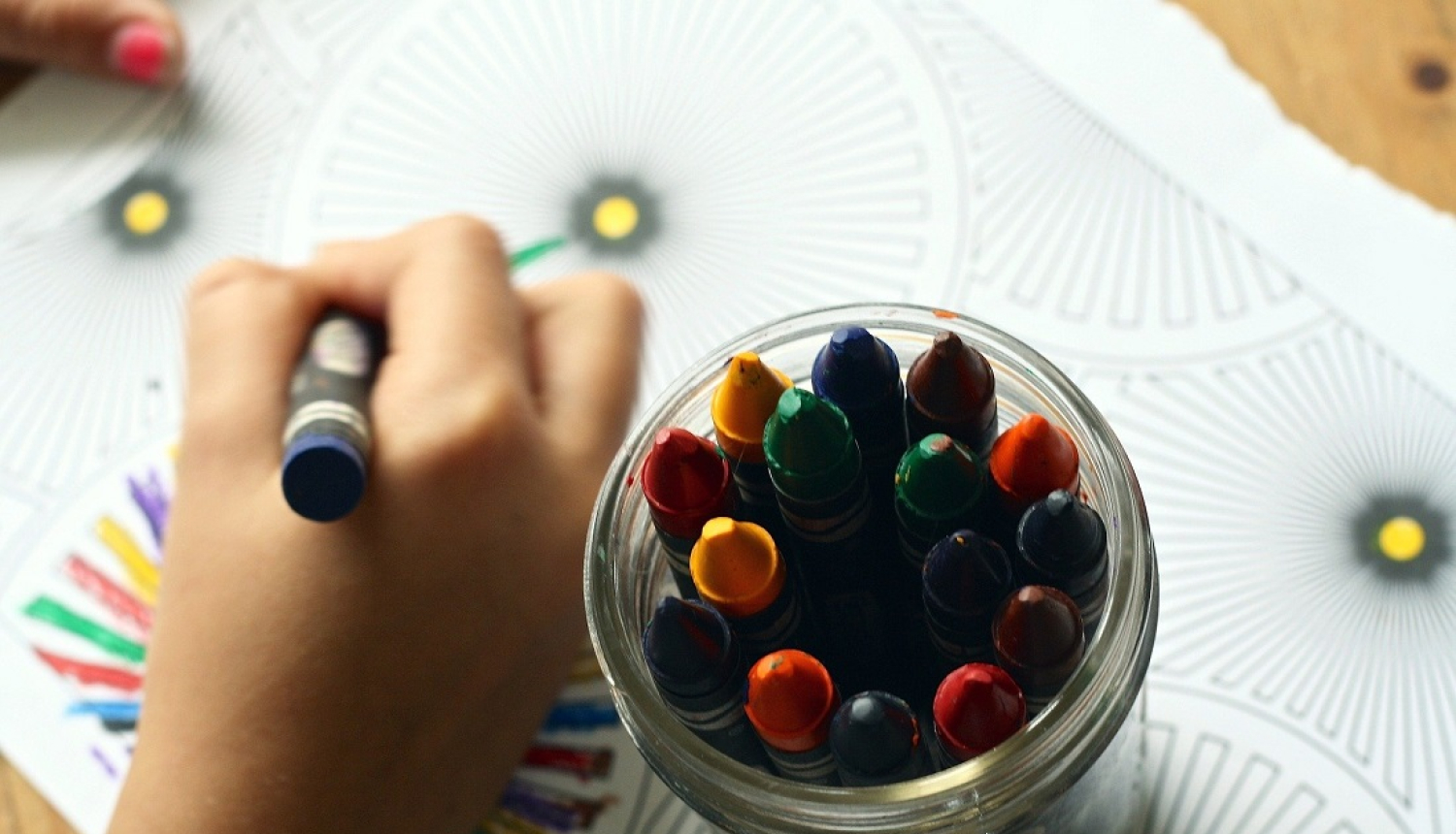 Bērna rokas, kas zīmē, un traukā krītiņi