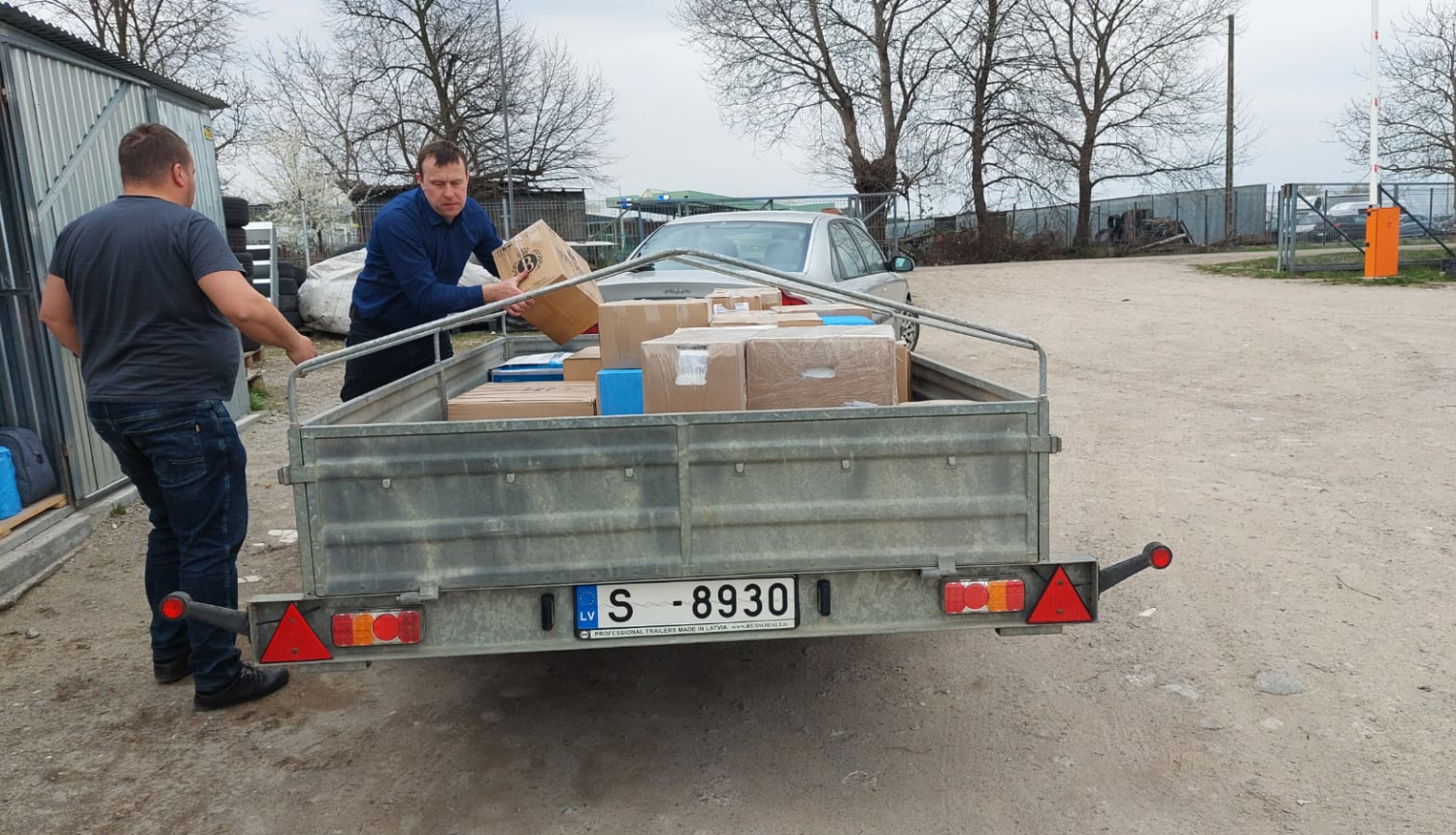 Divi vīrieši liek kastes auto piekabē