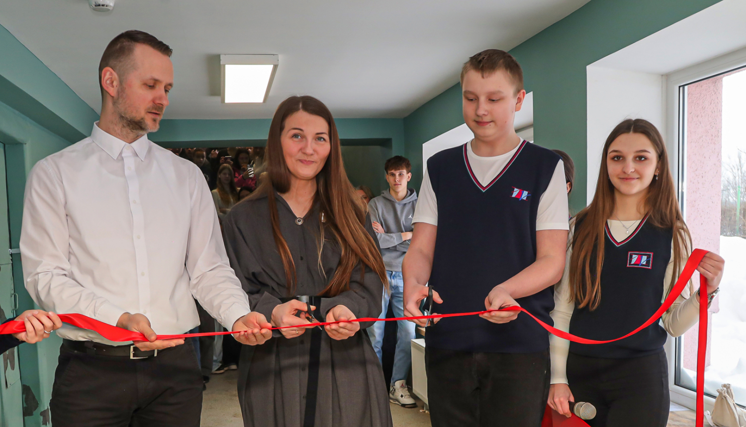 4 cilvēki griež sarkanu lentu