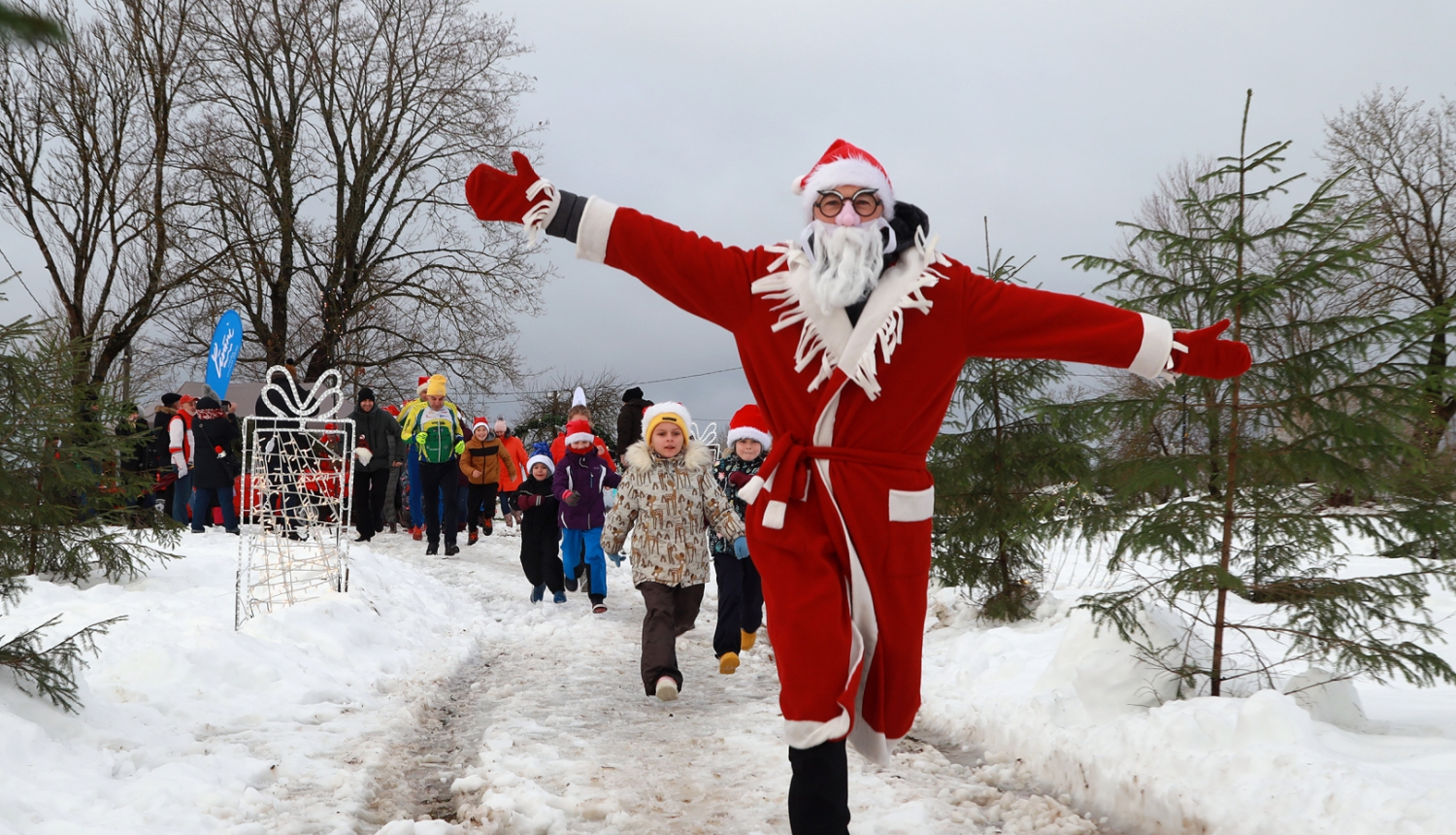 ziemassvētku vecītis skrien pa priekšu un iedzīvotāji aiz viņa