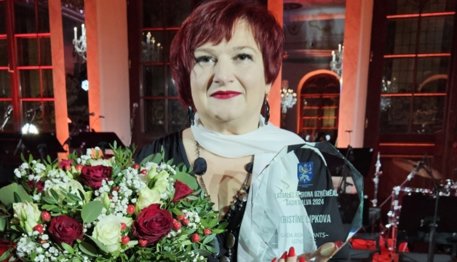 sieviete ar stikla balvu rokās un ziediem