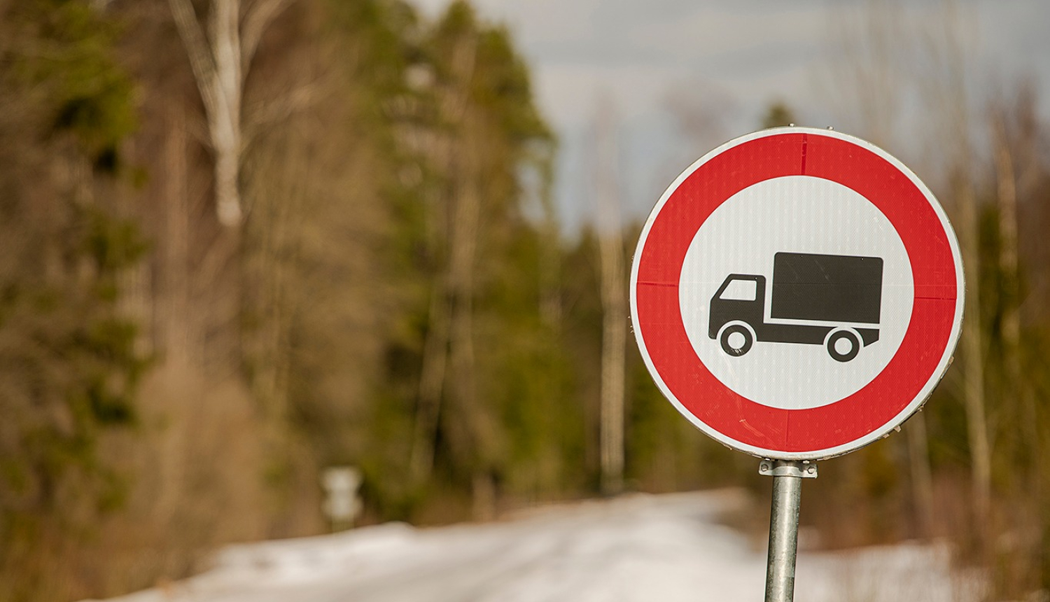 ceļa zīme ar smago auto unslikts ceļš fonā