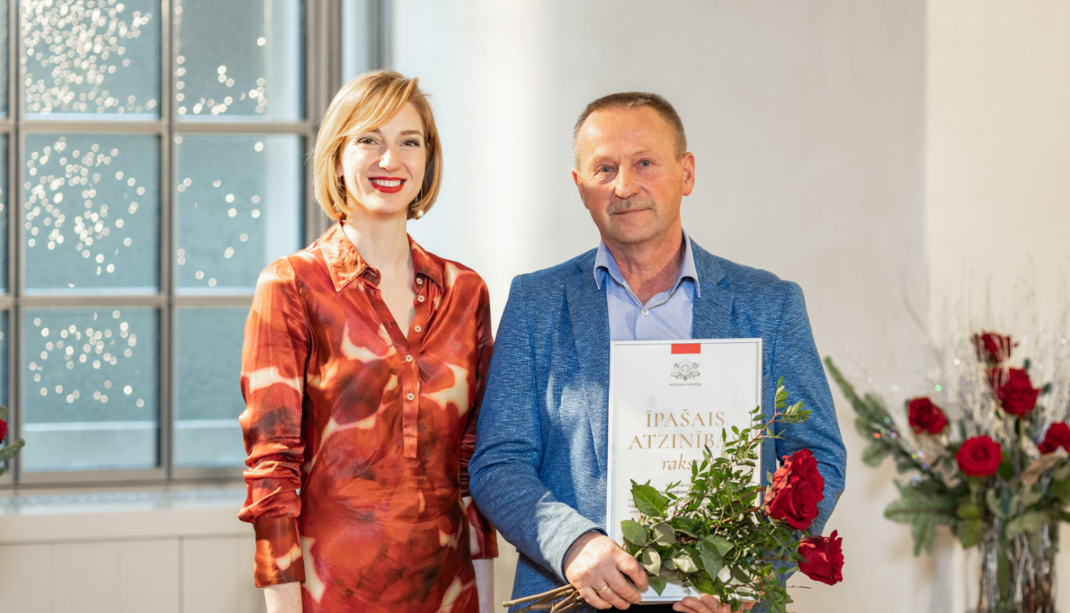 vīrietis un sieviete stāv ar apbalvojumiem rokā