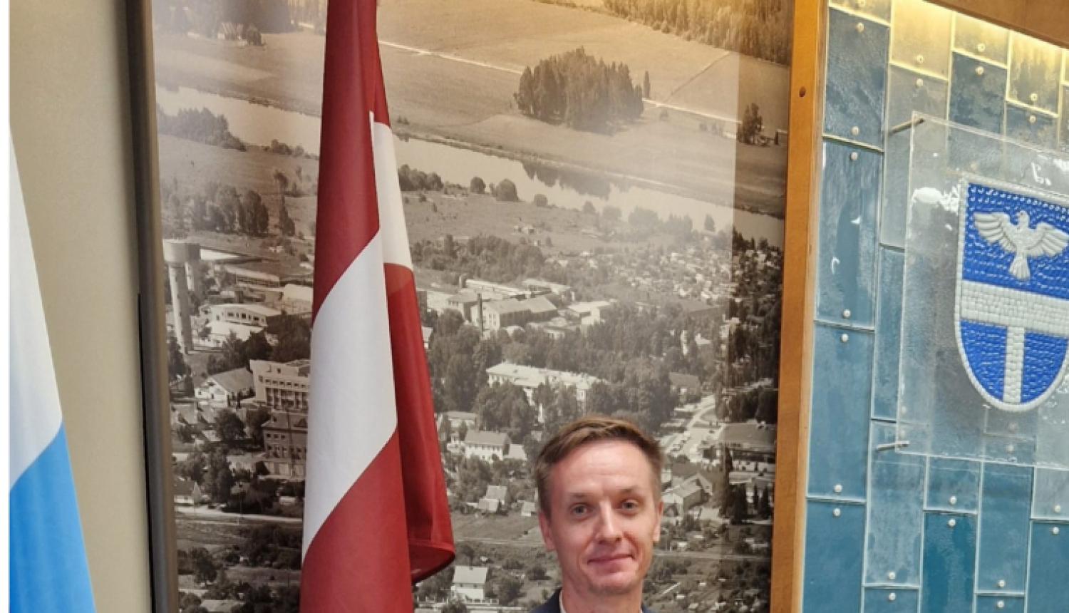 vīrietis stāv pie sienas ar karogiem