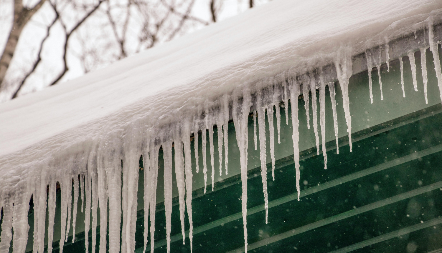Sniegs un lāstekas uz mājas jumta
