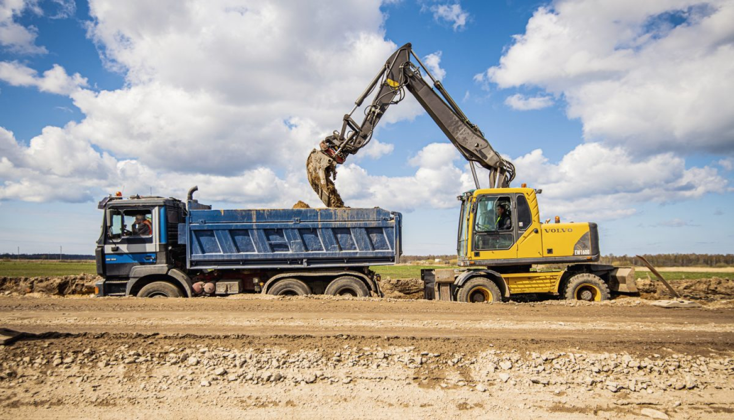 Kravas auto un ekskavators pie būvējama ceļa